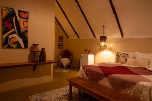a bedroom with a bed and a table and a lamp at Quinta dos Laranjais Chalés in Viçosa do Ceará