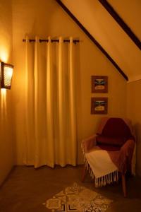 a room with a curtain and a chair with a rug at Quinta dos Laranjais Chalés in Viçosa do Ceará