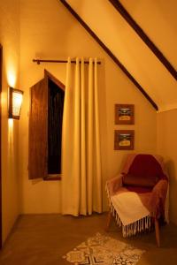 a room with a bed and a window with a curtain at Quinta dos Laranjais Chalés in Viçosa do Ceará