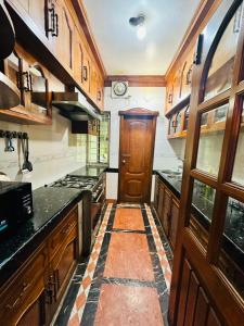 a kitchen with wooden cabinets and a wooden door at Sea Shell Service Apartment in Bāiljuri
