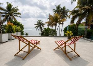 two chairs on a patio with the ocean in the background at Chez Colette in Matara