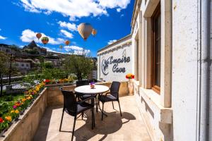 a balcony with a table and chairs and hot air balloons at Empire Cave Cappadocia in Göreme