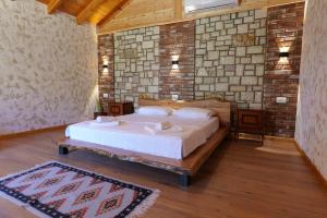 a bedroom with a bed and a brick wall at Bujtinat e Delvinës in Delvinë