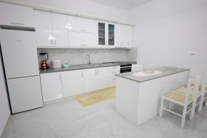 a white kitchen with white cabinets and a counter at Vila Lian Apartaments in Belsh