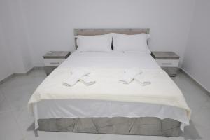 a bedroom with a bed with two slippers on it at Vila Lian Apartaments in Belsh