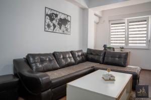 a living room with a leather couch and a table at М Apartments Shtip in Štip
