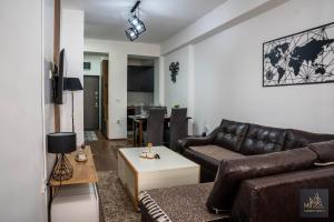a living room with a leather couch and a table at М Apartments Shtip in Štip