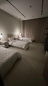 a room with three beds and a table at شاليه لوسيندا 2 in Baljurashi