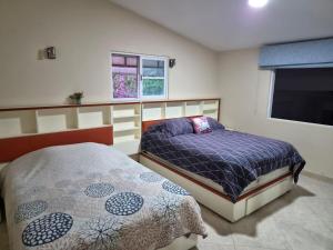 a bedroom with two beds and a flat screen tv at Cocoyoc Residential Estate in Texcalpan +36 photos