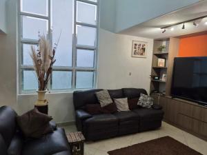 a living room with a leather couch and a flat screen tv at Cocoyoc Residential Estate in Texcalpan