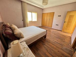a bedroom with a bed and wooden floors and a window at Villa Marina à Savannah Beach sidi rahal in Sidi Rahal