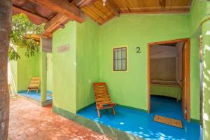 a green house with a chair and a bed at Casa Mahue in Puerto Escondido