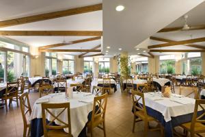 un ristorante con tavoli e sedie bianchi e finestre di TH Marina di Pisticci - Ti Blu Village a Marina di Pisticci