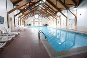 a large swimming pool with white chairs around it at Deer Park Condo 165D Vacation Rental near Loon Mountain in Woodstock