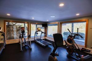 a gym with treadmills and elliptical machines in a room with windows at Deer Park Condo 165D Vacation Rental near Loon Mountain in Woodstock