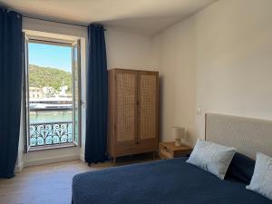 a bedroom with a bed and a large window at Les Appartements du Port in Bonifacio