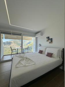 a bedroom with a large white bed with a balcony at Villa Ani in Borsh