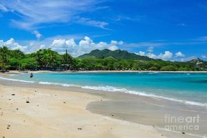 a beach with a person standing in the water at Las Tres Casitas in San Felipe de Puerto Plata