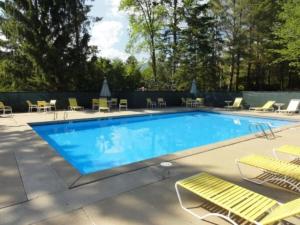 a large swimming pool with chairs and a table at Windsor Hill E53 WV Updated Pet Friendly Windsor Hill Condo in Waterville Valley