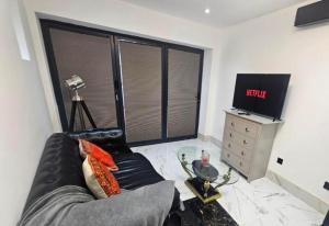 a living room with a black leather couch and a television at Heaven in Sutton