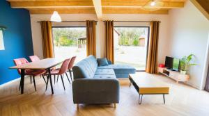 a living room with a blue couch and a table at Rumiane Chatki - Domki z Jacuzzi i Basenem in Rybno