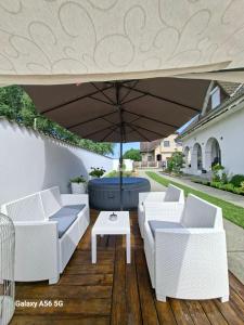a patio with white furniture under an umbrella at Sarkcsillag Vendégház in Kiskőrös