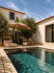 a swimming pool with an umbrella and a house at A Casa Brava in Santarém