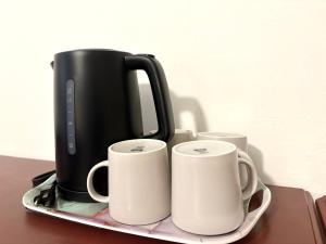 two coffee cups on a tray with a coffee pot at Hotel La Residence du Voyageur in Montreal