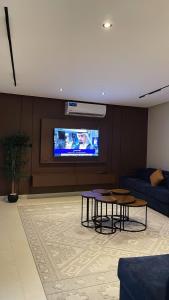 a living room with a couch and a tv on a wall at شاليه لوسيندا 2 in Baljurashi