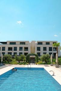 a person swimming in a pool in front of a building at Luxurious Bohemian Residence with Pool in Tivat