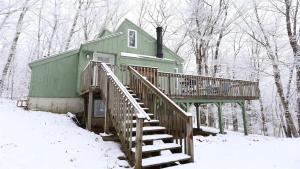 a green house with a staircase in the snow at Green Circle 29 Estates Pet Friendly Private Home in Waterville Estates in Campton