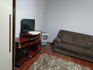 a living room with a couch and a television at cantinho da paz in Dourados +5 photos