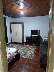 a living room with a bed and a tv at cantinho da paz in Dourados