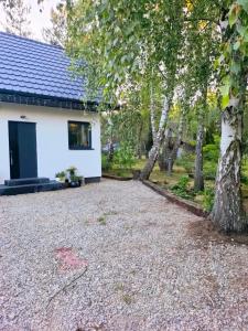 a gravel driveway in front of a white house at Siedlisko Niwy in Łęki Szlacheckie