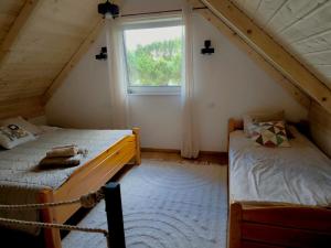 two beds in a room with a window at Siedlisko Niwy in Łęki Szlacheckie