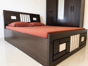 a large bed with a wooden frame and red sheets at Sai Mahima Stays in Shirdi