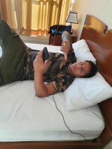 a woman laying on a bed holding a remote control at Hotel Roman in Pucallpa