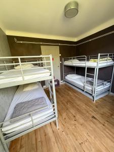 three bunk beds in a room with wooden floors at Le Kompost'l dortoir en gîte 4 place in Saint-Privat-dʼAllier
