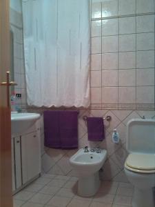 ポルト・エンペードクレにあるSole & Mareのバスルーム(トイレ、紫色のタオル付き洗面台付)