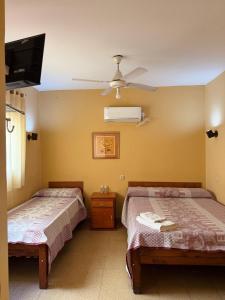 two beds in a room with a ceiling fan at Hotel Soles de Lidia in Monte Cristo
