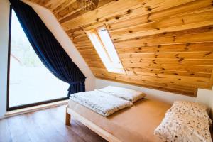 a bedroom with a wooden ceiling and a bench with a window at Rumiane Chatki - Domki z Jacuzzi i Basenem in Rybno