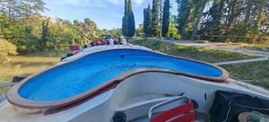 a boat sitting in a river with a blue water at Péniche ALEGRIA in Poilhès