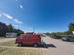 a red van parked in a parking lot at Retro Kamper Jastarnia in Jastarnia