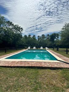 a swimming pool with two chairs in the grass at Casa Casona Las Toscas in Miramar