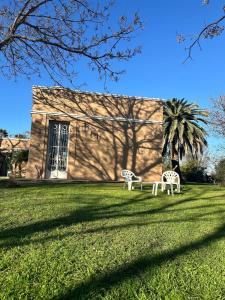 two white benches in the grass in front of a building at Casa Casona Las Toscas in Miramar