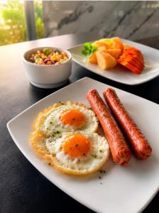 two plates of food with eggs and sausage on a table at TAMA Hotel Santa Marta in Santa Marta