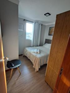 a bedroom with a bed with white sheets and a window at Apartamento completo e perfeito, Ao lado da Weg in Jaraguá do Sul