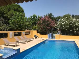 a swimming pool with lounge chairs next to a yellow wall at Résidence les Caraibes in Sérignan