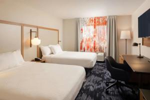 a hotel room with two beds and a desk at Fairfield Inn & Suites Lansing West in Delta Center Township