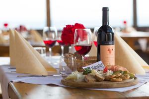 stół z butelką wina i talerzem jedzenia w obiekcie Berggasthof Häusler w mieście San Lorenzo di Sebato